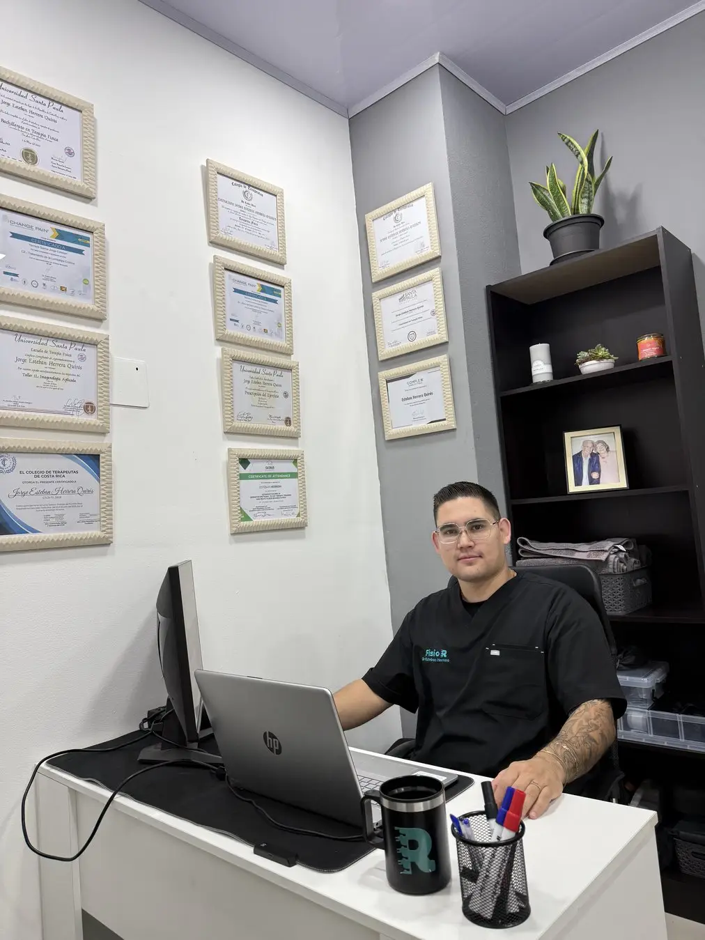 Esteban Herrera Quirós en el consultorio de FISIO R, con sus títulos en la pared