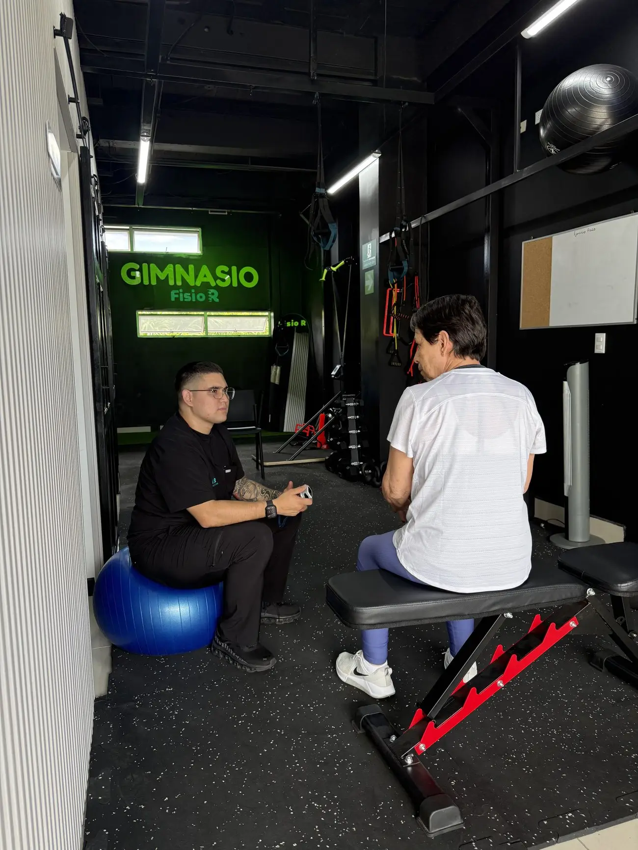 Sesión de ejercicio terapéutico con una persona adulta mayor en el gimnasio de FISIO R